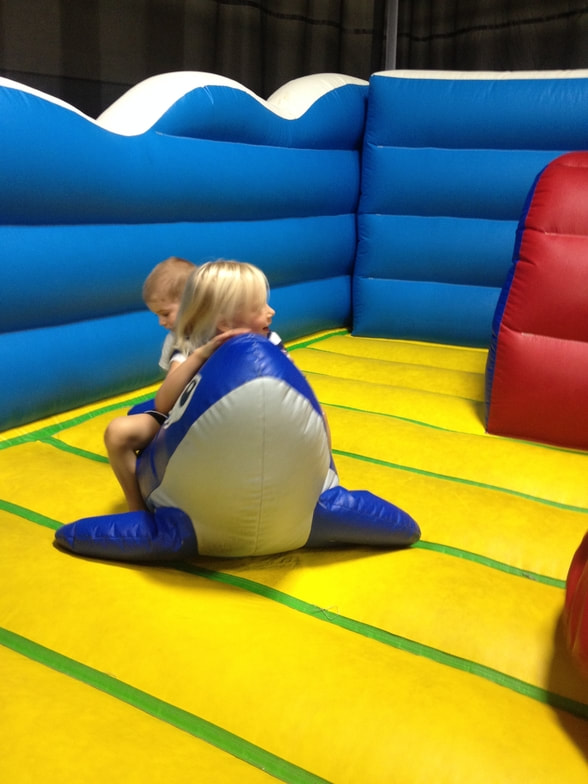 Two children riding a whale in a bouncy house