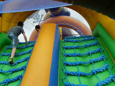 Young child climbing up a bouncy castle climbing wall