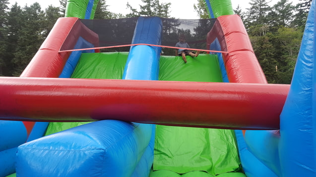 Young boy at the top of small double blow up slide
