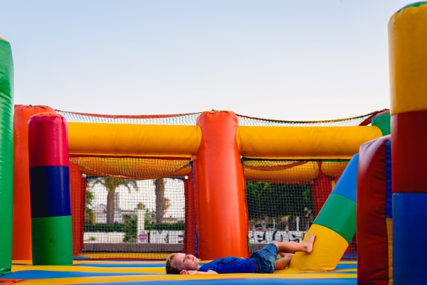 young boy laying down in a bouncy castle obstacle course