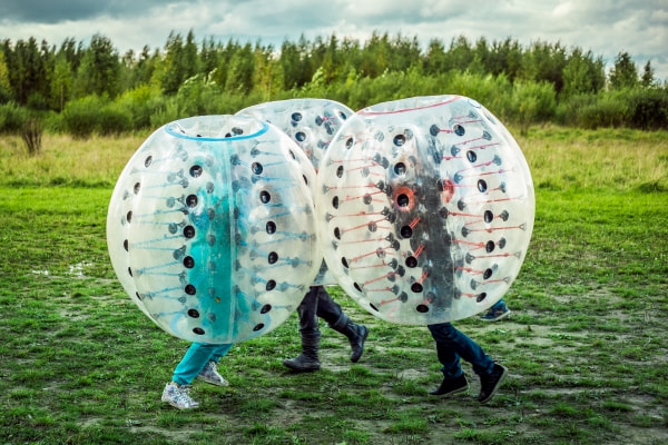 Three children bouncing into each other while being enclosed in a large blow up ball 