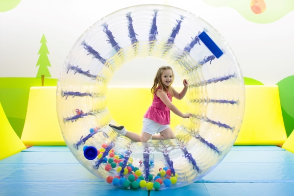 Young girl crawling inside a blow up hamster wheel 