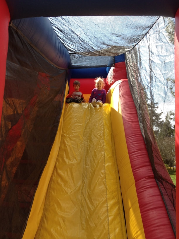 Two children sitting at the top of a bouncy castle slide